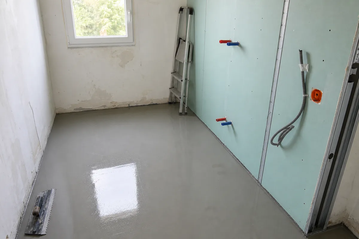 Salle de bain en chantier avec ragréage du sol frais et cloison hydrofuge posée